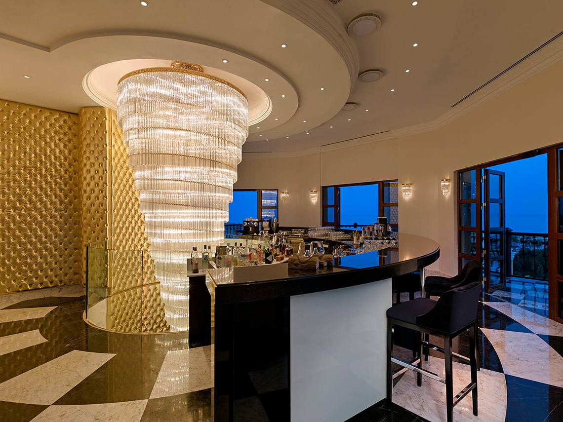 Innenansicht der Bar im Titanic Mardan Palace mit großem Kristallleuchter und Blick auf die Stadt.