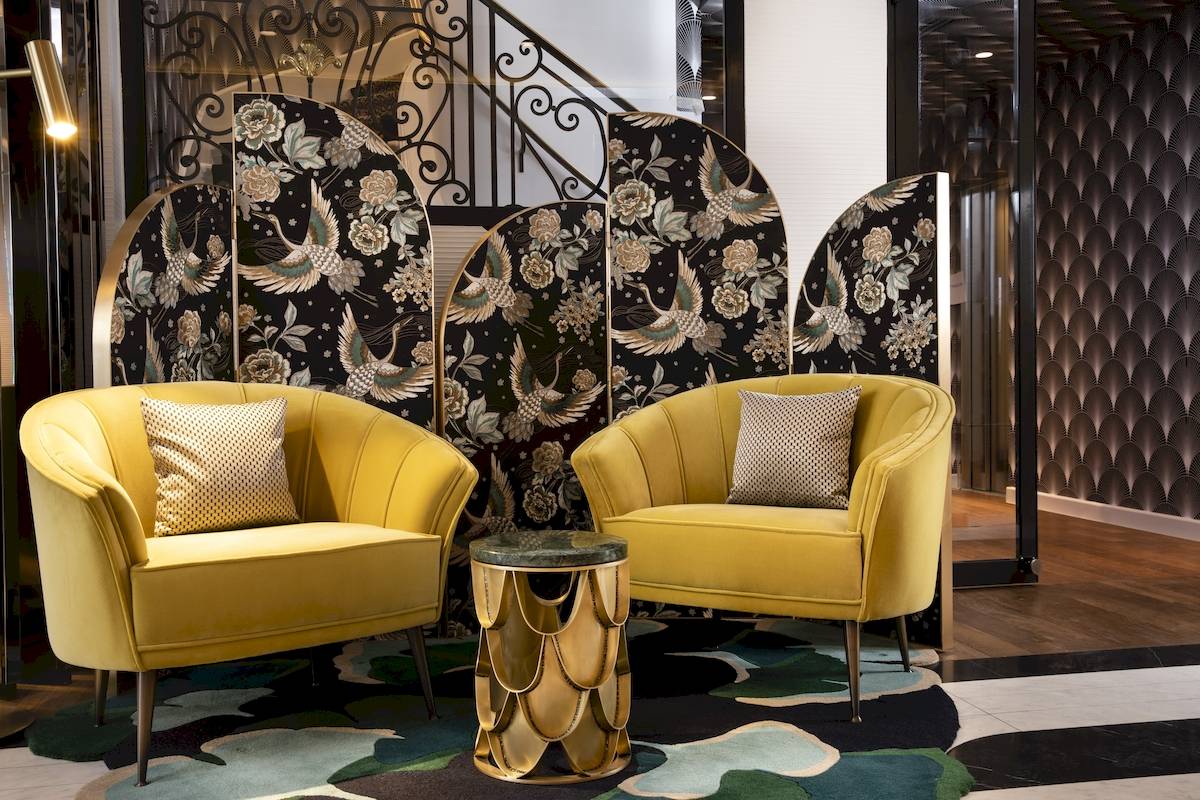 Zwei gelbe Sessel stehen in der Hotellobby von Victor Hugo Paris Kléber neben einem Tisch.