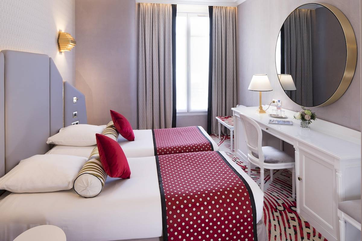 Zwei Doppelbetten mit roten und weißen Punkten in einem eleganten Hotelzimmer, Victor Hugo Paris Kléber.