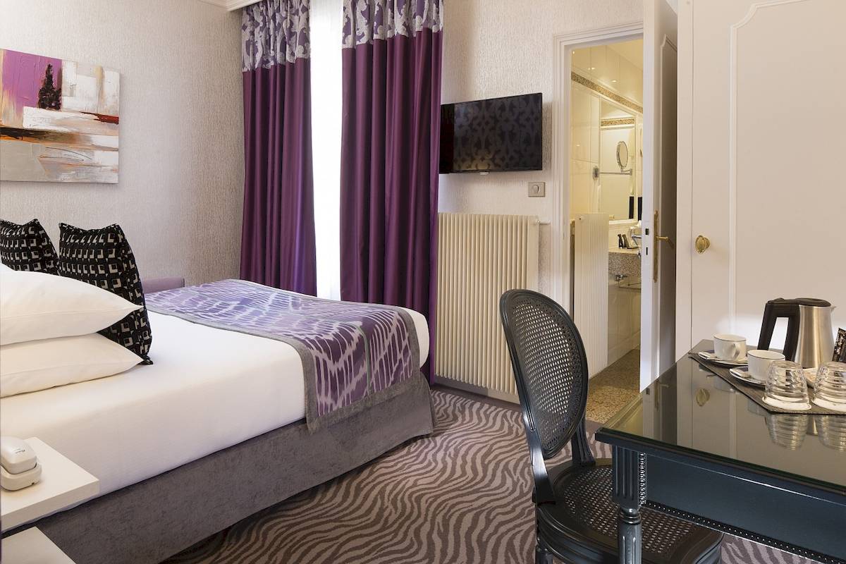 Hotelzimmer mit Bett, Fernseher, Schreibtisch und Sessel im Victor Hugo Paris Kléber