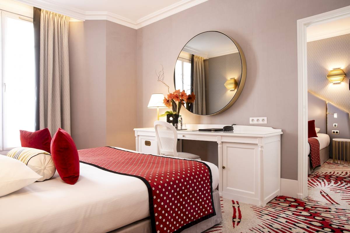 Ein elegantes Hotelzimmer mit einem Bett, Schreibtisch und einem Spiegel im Victor Hugo Paris Kléber Hotel.