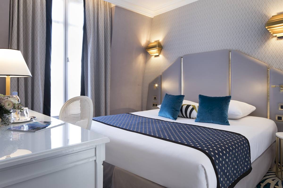 Schlafzimmer im Victor Hugo Paris Kléber Hotel mit Bett, Dekor und Schreibtisch.