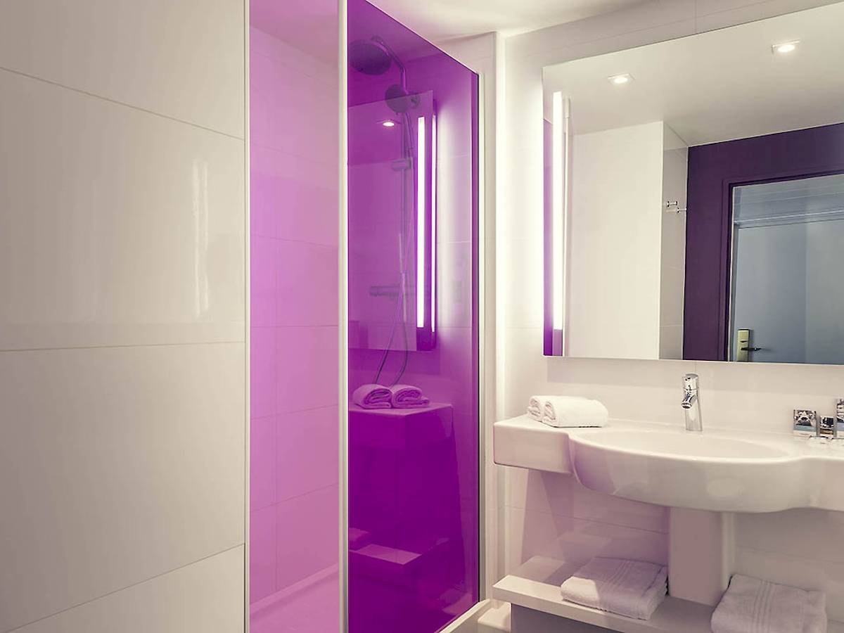 Badezimmer im Mercure Paris Bercy Bibliothèque Hotel mit violetter Dusche und weißem Waschbecken