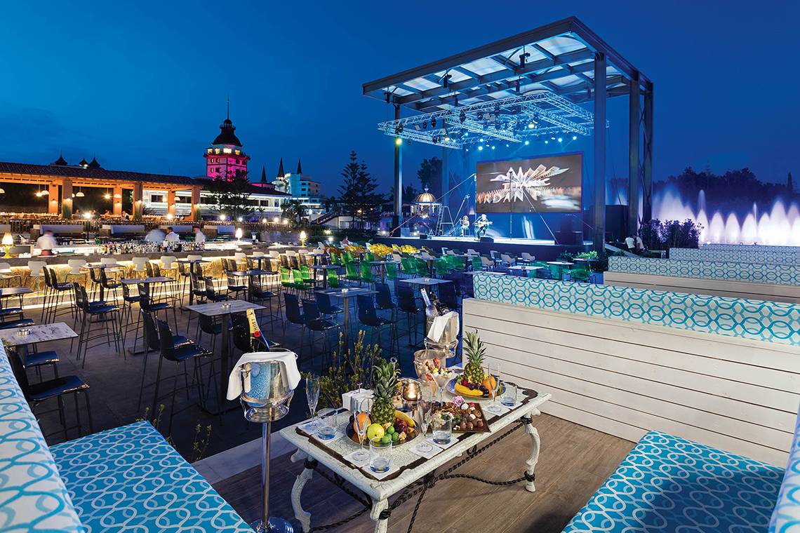 Abendveranstaltung im Freien beim Titanic Mardan Palace Hotel mit Bühne, Bar und Sitzbereichen.