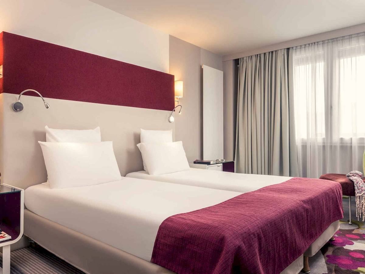 Doppelzimmer im Mercure Paris Bercy Bibliothèque mit zwei Betten und roten Kopfteilen.