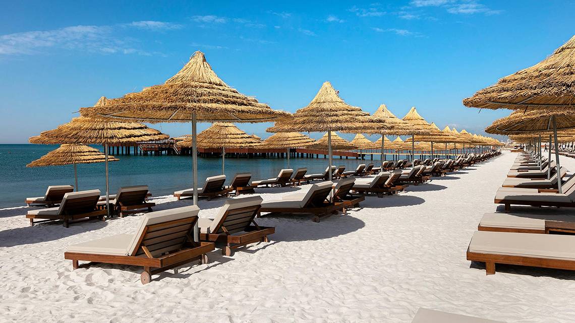 Strand mit Sonnenliegen und Sonnenhuten am Titanic Mardan Palace Hotel