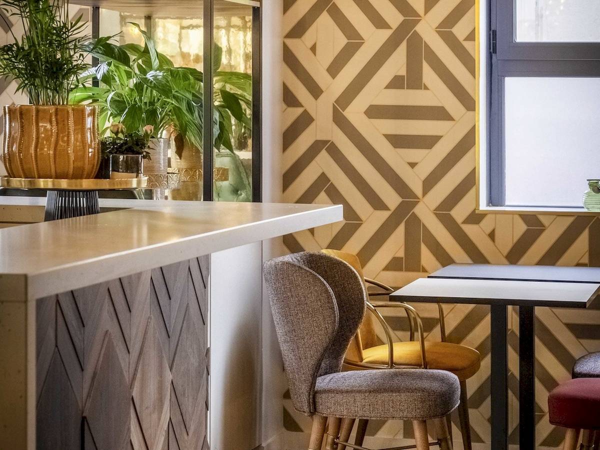 Innenansicht der Bar des Mercure Paris Bercy Bibliothèque Hotels mit Pflanzen, Stühlen und Tischen.