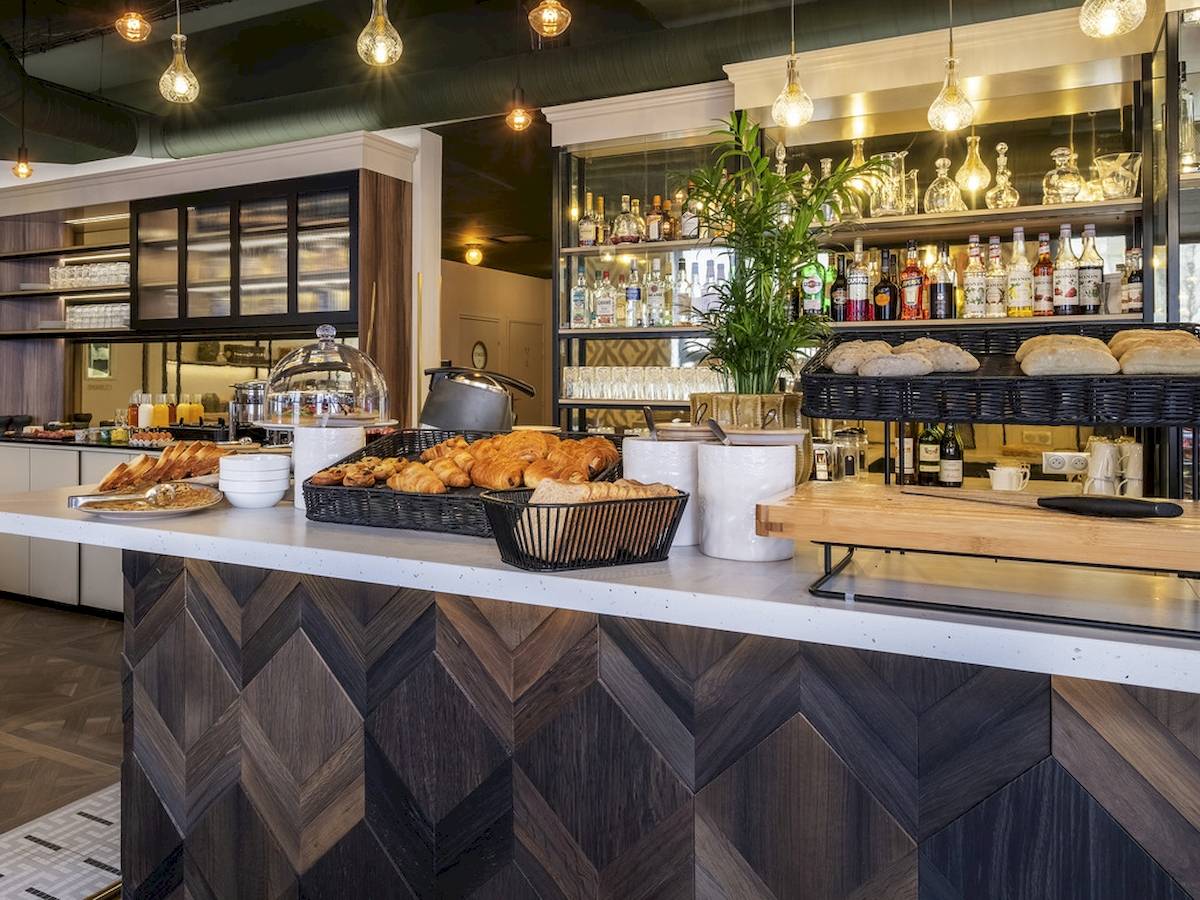 Frühstücksbereich im Mercure Paris Bercy Bibliothèque mit Croissants, Brot und Getränken.