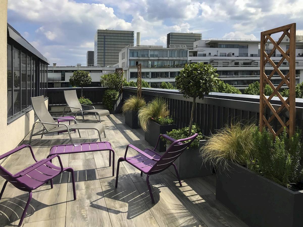 Terrasse mit Lounge-Stühlen und Pflanzen im Freien, Blick auf die Stadt