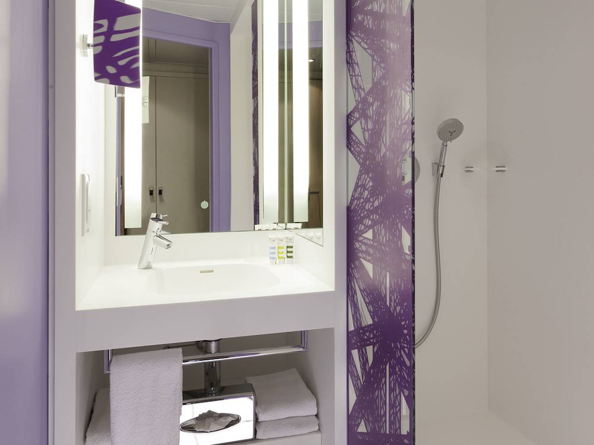 Badezimmer im Mercure Paris Centre Tour Eiffel Hotel mit violetten Wandmustern und einer Dusche.