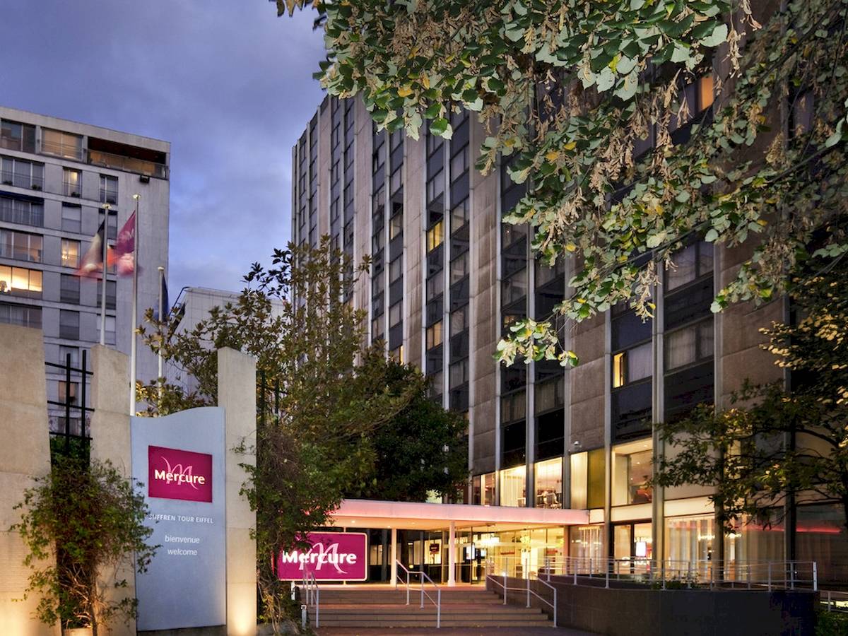 Außenansicht des Mercure Paris Centre Tour Eiffel Hotels bei Nacht mit Beleuchtung und Bäumen