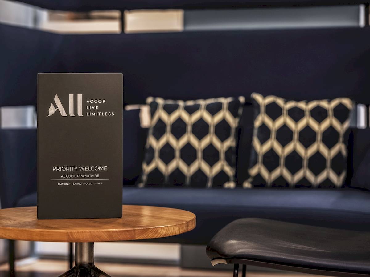Buch mit dem Titel Priority Welcome von Accor Live Limitless vor einem blauen Sofa