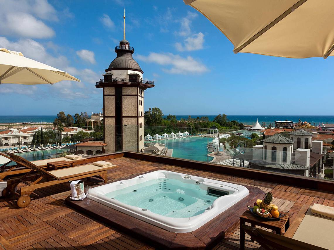 Hotelterrasse mit Jacuzzi und Ausblick auf das Meer und eine historische Turmstruktur.