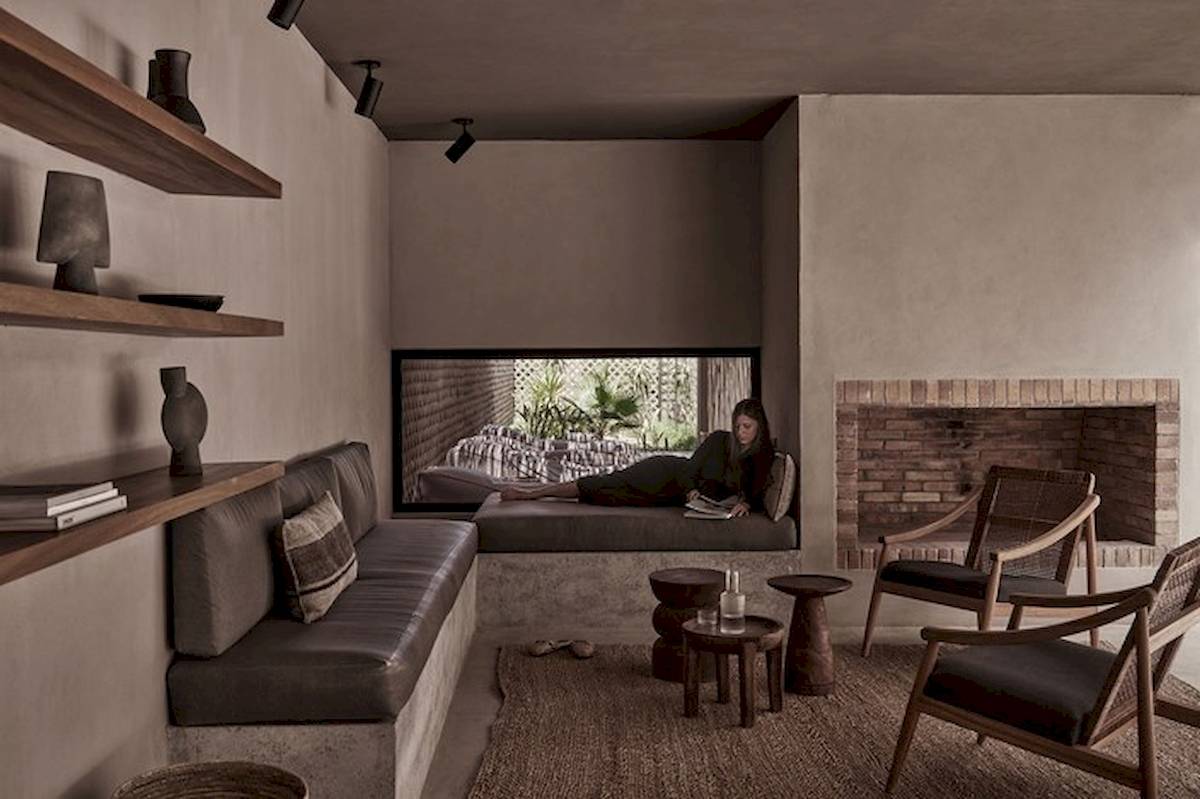 Innenbereich des Casa Cook El Gouna Hotels mit Frau auf Liege, Couch, Holztischen und Sesseln.