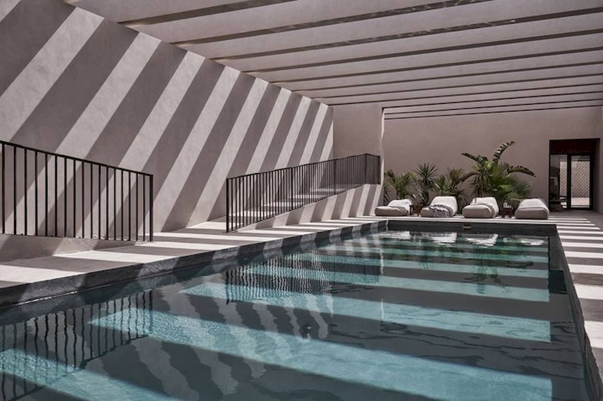 Innenpool des Casa Cook El Gouna Hotels mit stilvollen schwarzen Geländern und umgeben von Loungemöbeln.