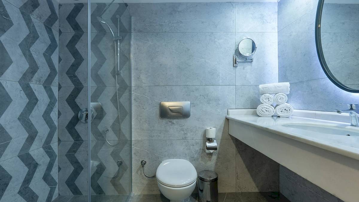 Das Badezimmer im Sunrise Queen Luxury Hotel mit einer Duschkabine, einem Waschbecken und einem Spiegel.