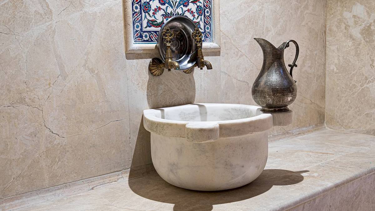 Ein Badezimmer mit einem Marmorwaschbecken und einer alten Kruecke an der Wand.