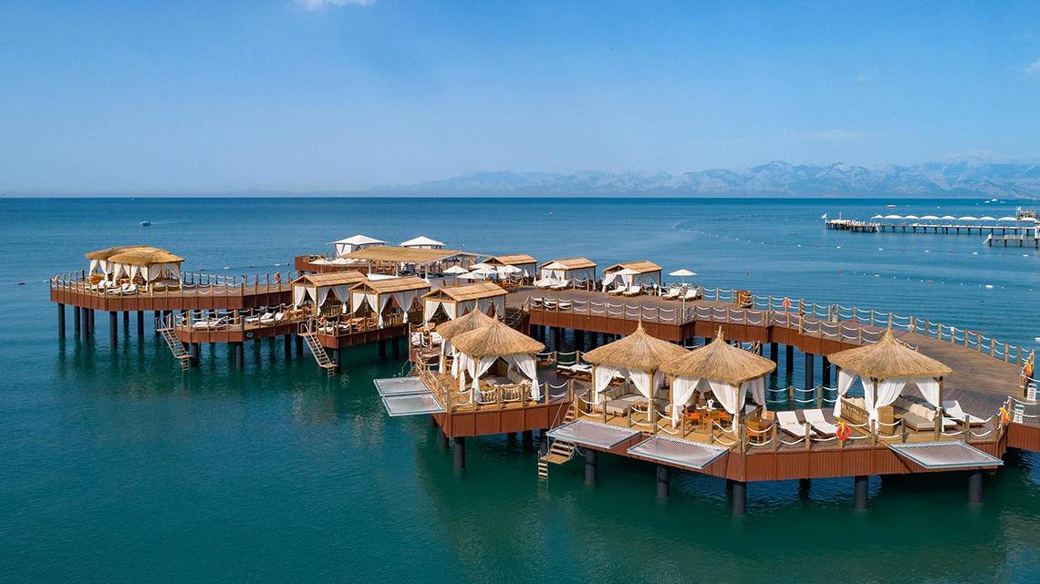 Luftaufnahme des Titanic Mardan Palace Hotels mit Wasserbungalows und Loungebereichen am Meer