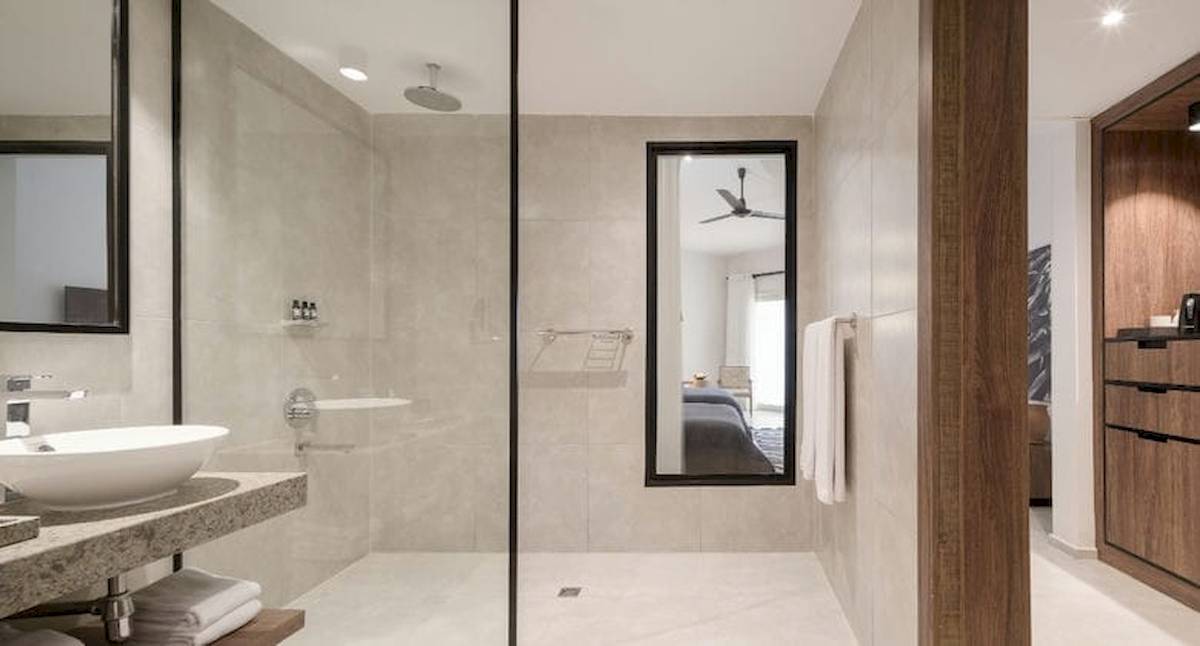 Badezimmer im Serry Beach Resort mit Regendusche, Spiegel und modernem Design.