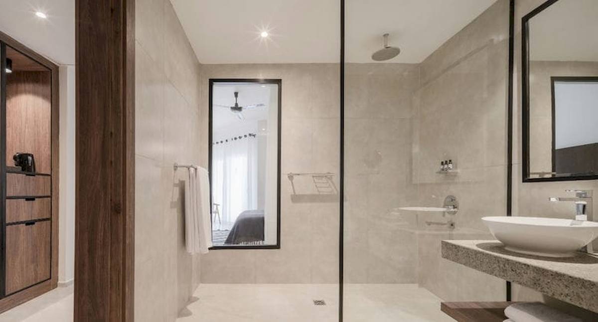 Ein modernes Badezimmer im Serry Beach Resort mit einer Duschkabine, einem Waschbecken, einem Spiegel und Holzmöbeln.