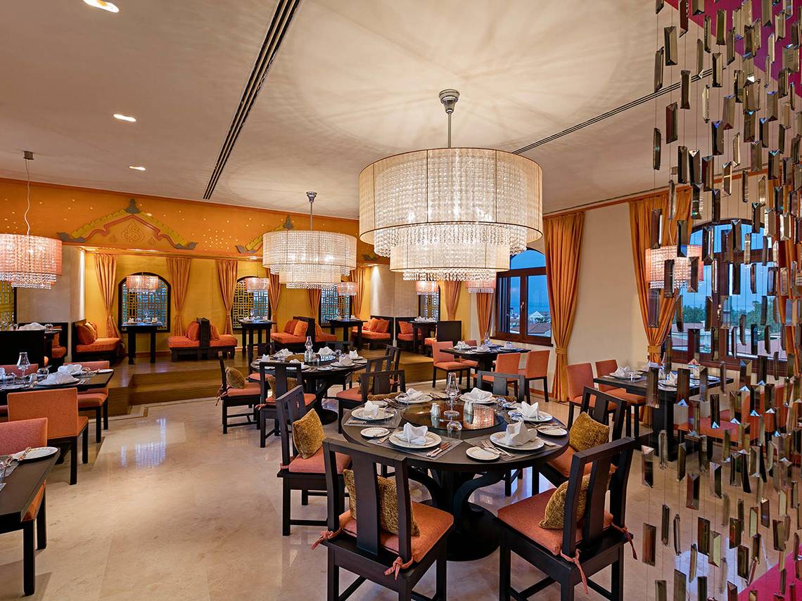 Innenansicht des Restaurants Titanic Mardan Palace mit runden Tischen und kristallenen Kronleuchtern.
