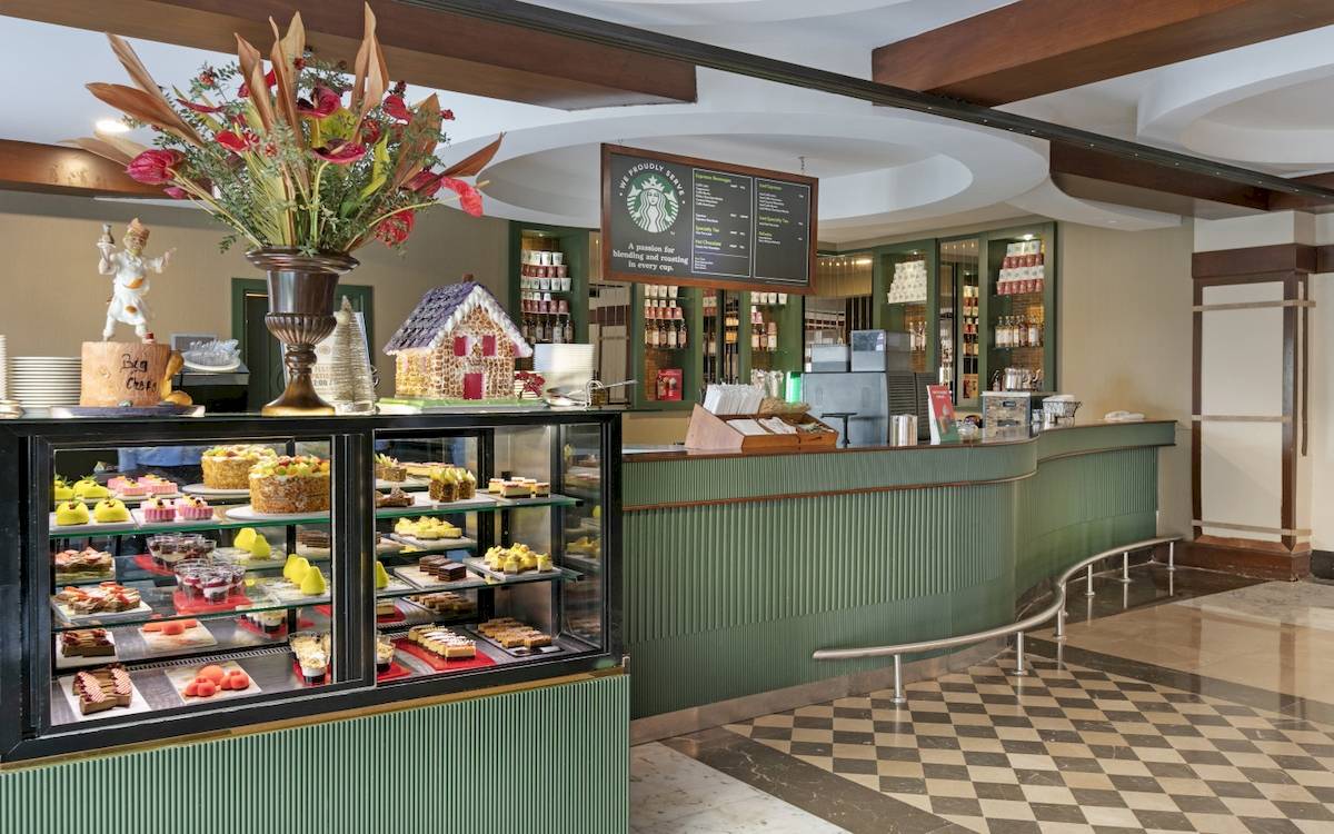 Innenansicht des Cafés im Dobedan Exclusive Hotel & Spa Belek mit Kuchendisplay und grünen Theken.
