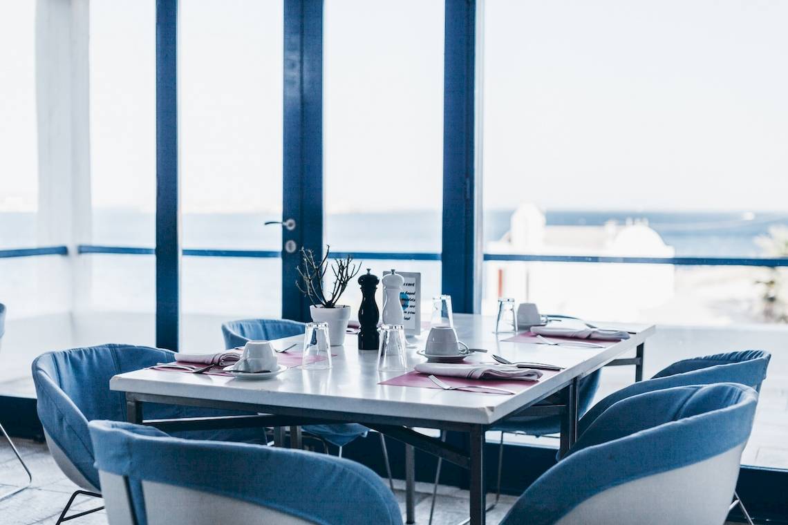 Ein Tisch im Restaurant des Mykonos Theoxenia Boutique Hotels mit Blick auf das Meer.