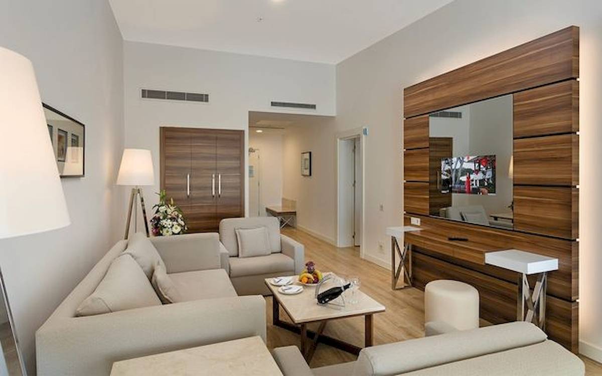 Hotelsuite-Wohnbereich mit Sofa, Tisch und Fernseher im Limak Atlantis Deluxe Hotel & Resort.