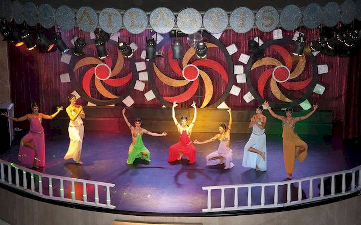 Sechs Tänzerinnen in farbenfrohen Kostümen führen eine Show auf der Bühne des Limak Atlantis Deluxe Hotel & Resort auf.
