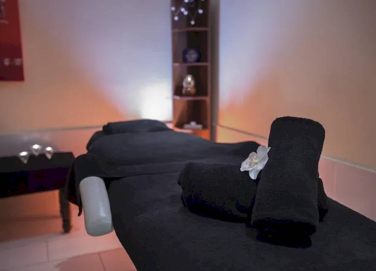 Massagebehandlungsliege im Hipotels Mediterraneo mit schwarzen Handtüchern und einer weißen Blume.