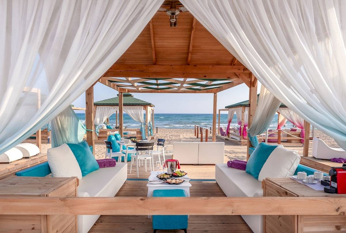 Strand-Loungebereich des Sentido Kamelya Fulya Hotels mit weißen und blauen Möbeln und Blick auf das Meer.