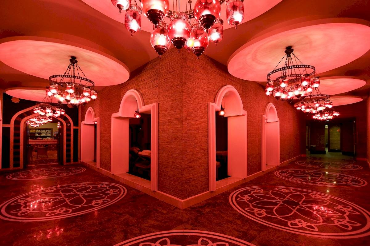 Roter Korridor im Sentido Kamelya Fulya Hotel mit roten Kronleuchtern und geometrischen Bodenmustern.