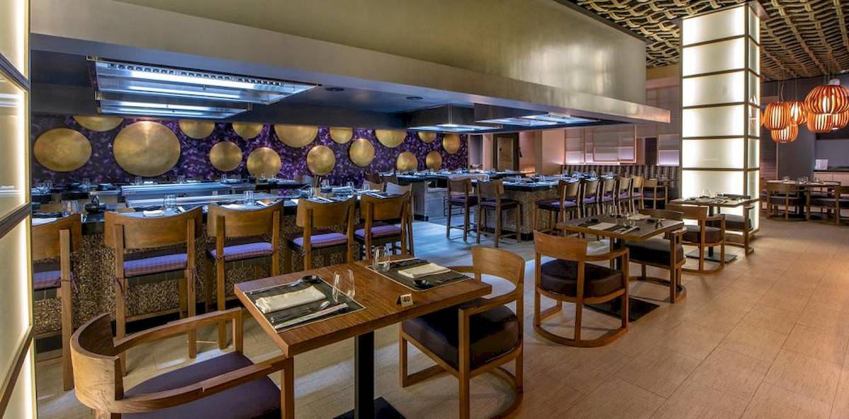Innenansicht des Restaurants im Lopesan Costa Bavaro Resort Spa & Casino mit Holztischen und Stühlen.