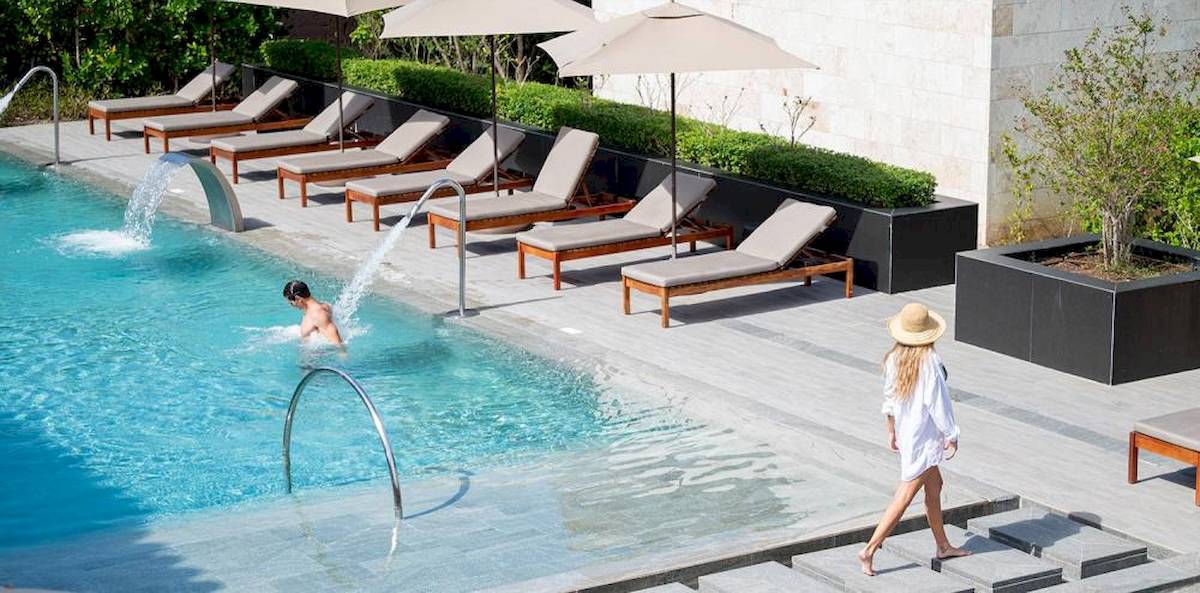 Schwimmbad im Lopesan Costa Bavaro Resort Spa & Casino mit Sonnenliegen, Sonnenschirmen und Gästen
