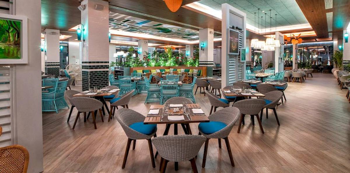 Innenansicht des Restaurants im Lopesan Costa Bavaro Resort Spa & Casino mit blauen Stühlen und Holztischen.