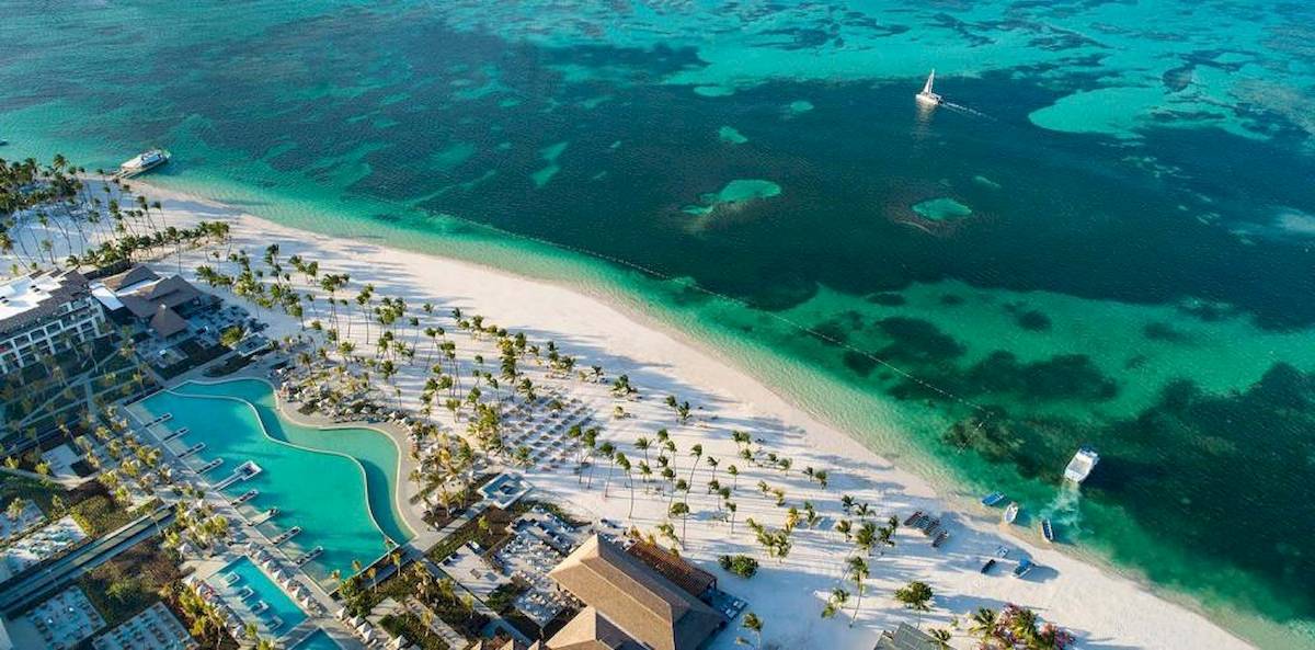 Luftaufnahme des Lopesan Costa Bavaro Resorts mit einem großen Pool, weißen Stränden und mehreren Booten im Wasser.