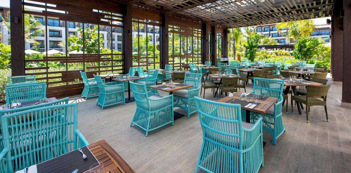 Außenbereich eines Gartenrestaurants mit blauen Stühlen und Tischen im Lopesan Costa Bavaro Resort Spa & Casino.