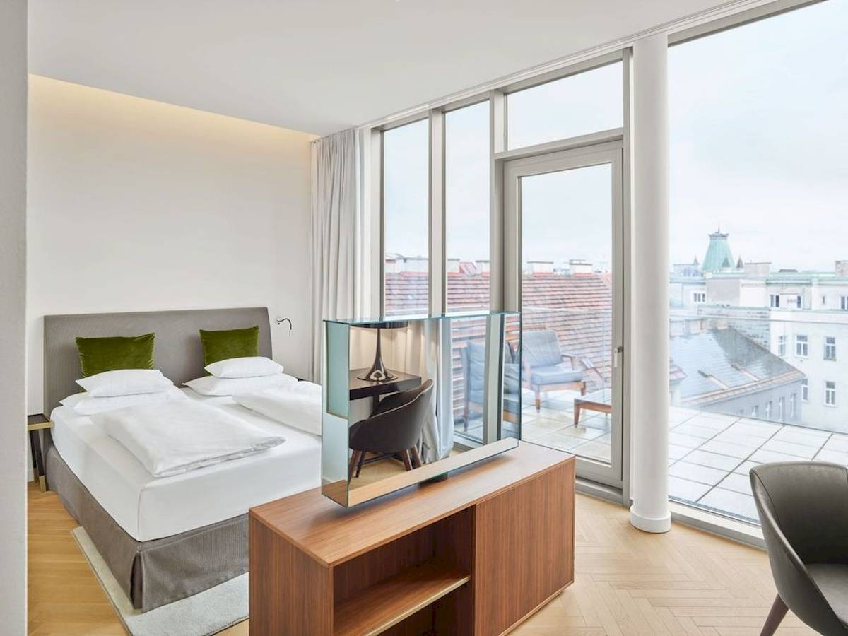Innenansicht eines Zimmers im MAXX by Steigenberger Vienna Hotel mit Doppelbett, Schreibtisch und Aussicht.