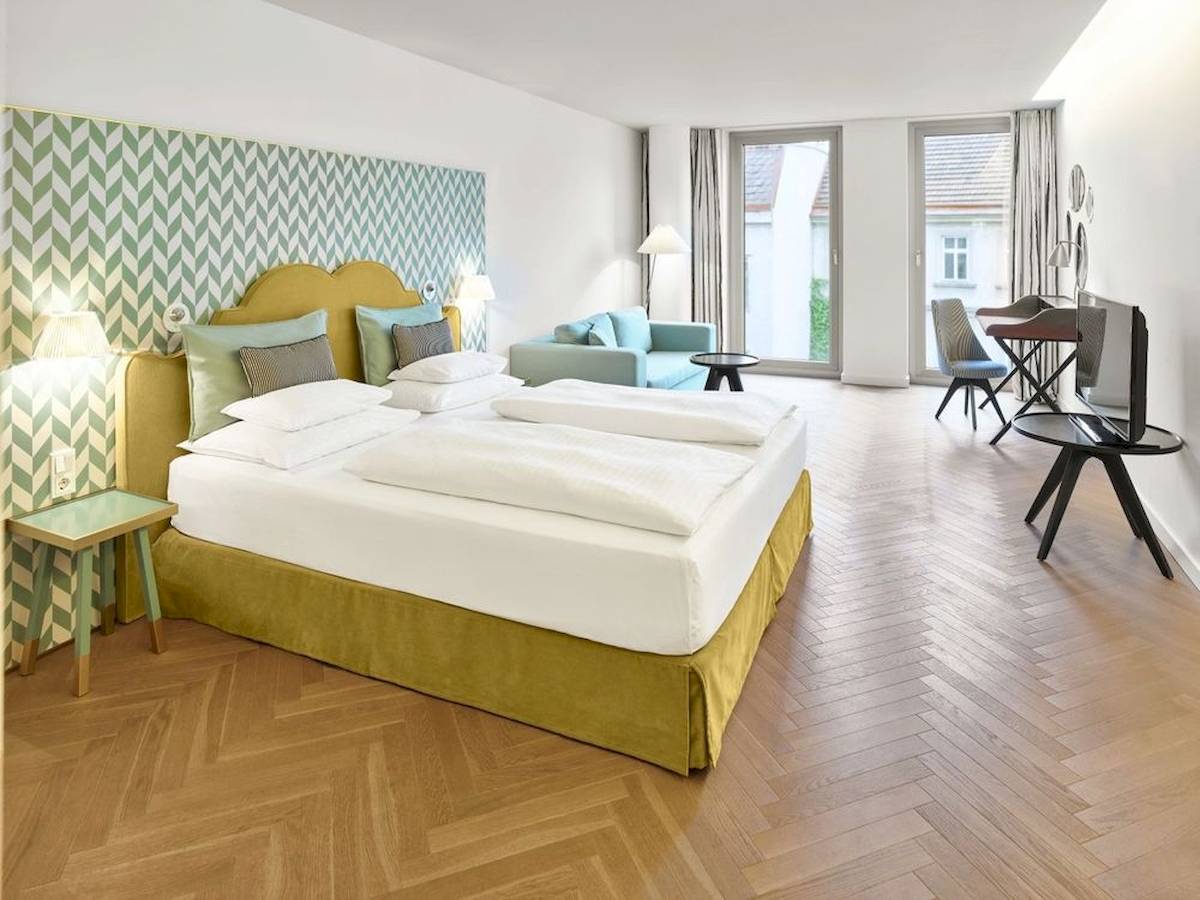 Schlafzimmer im MAXX by Steigenberger Vienna mit grüner Wandverkleidung und zwei Betten