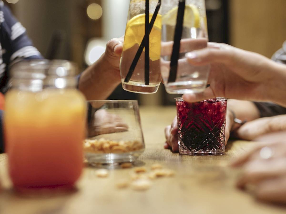 Gäste, die an einem Tisch sitzen und verschiedene Getränke mit Zitronenscheiben und Strohhalmen trinken, im Ibis Wien Mariahilf.