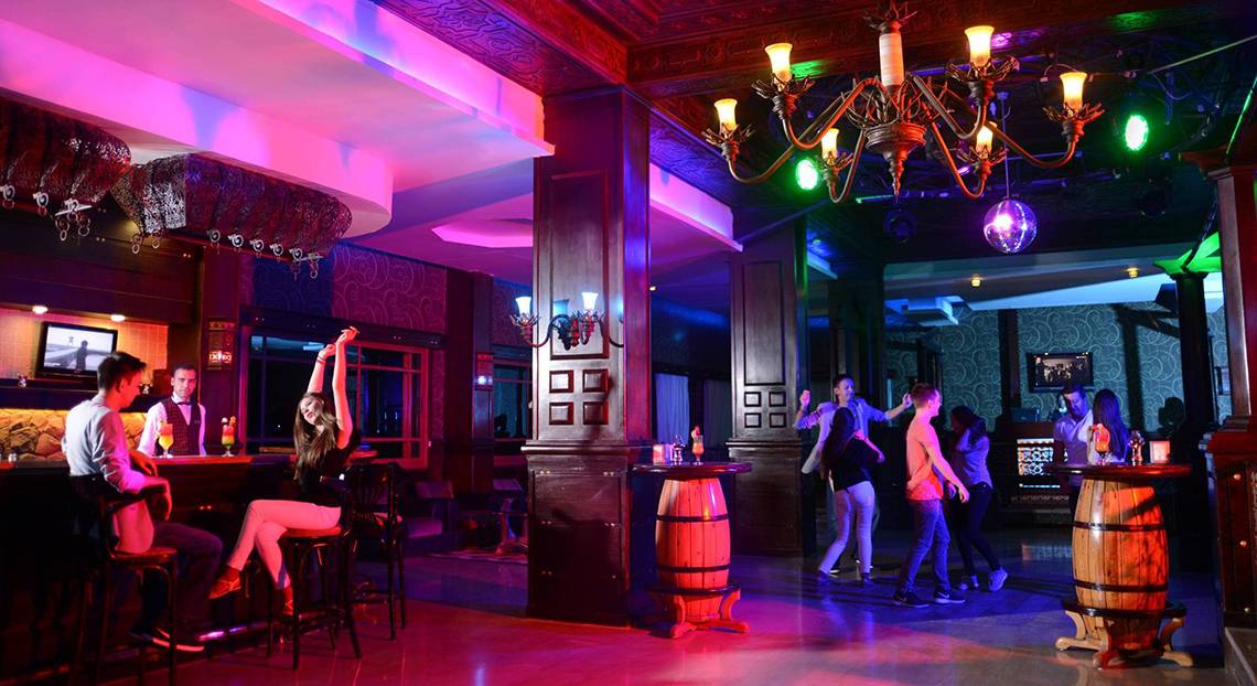Innenansicht der Bar im Pickalbatros Palace Resort, Hurghada, mit Gästen, Kronleuchter und bunten Lichtern.