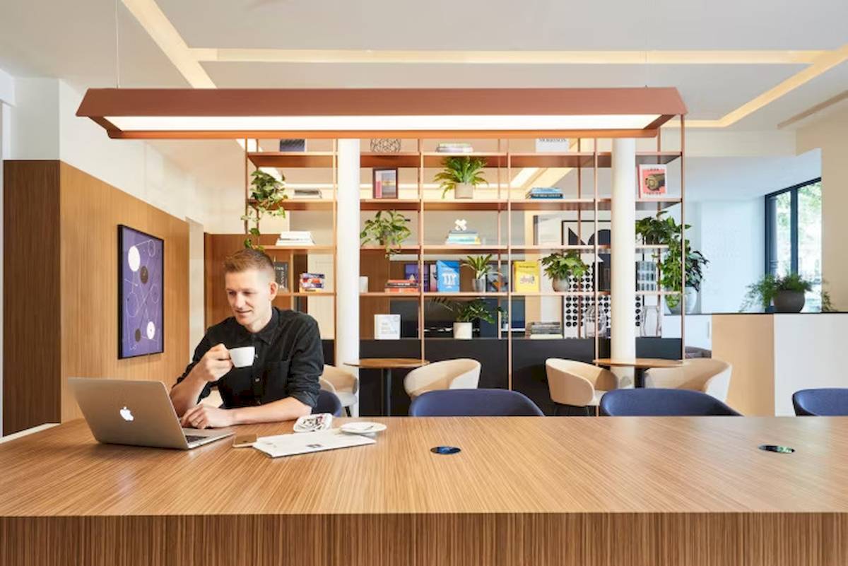 Ein Mann sitzt mit Laptop und Kaffee in einem Hotellobby.