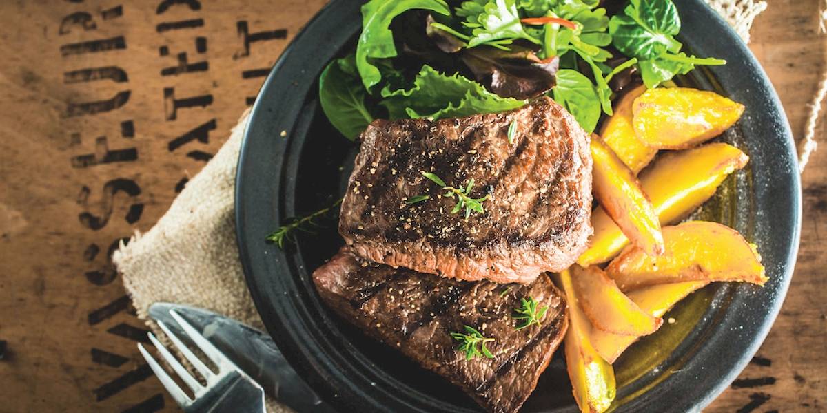 Ein Teller mit gegrilltem Steak und Pfirsichscheiben im Club Marvy Hotel.