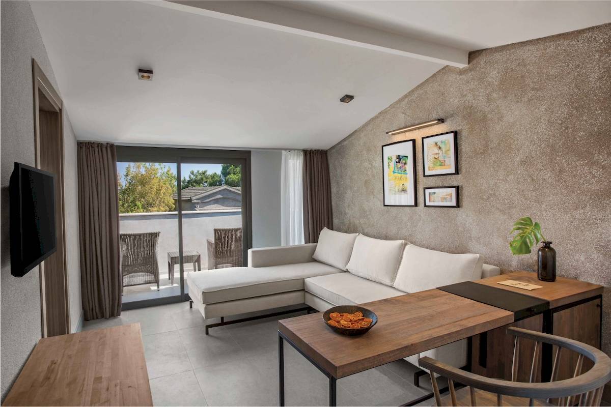 Inneneinrichtung eines Zimmers im Club Marvy Hotel mit Sofa, Tisch und Fernseher.