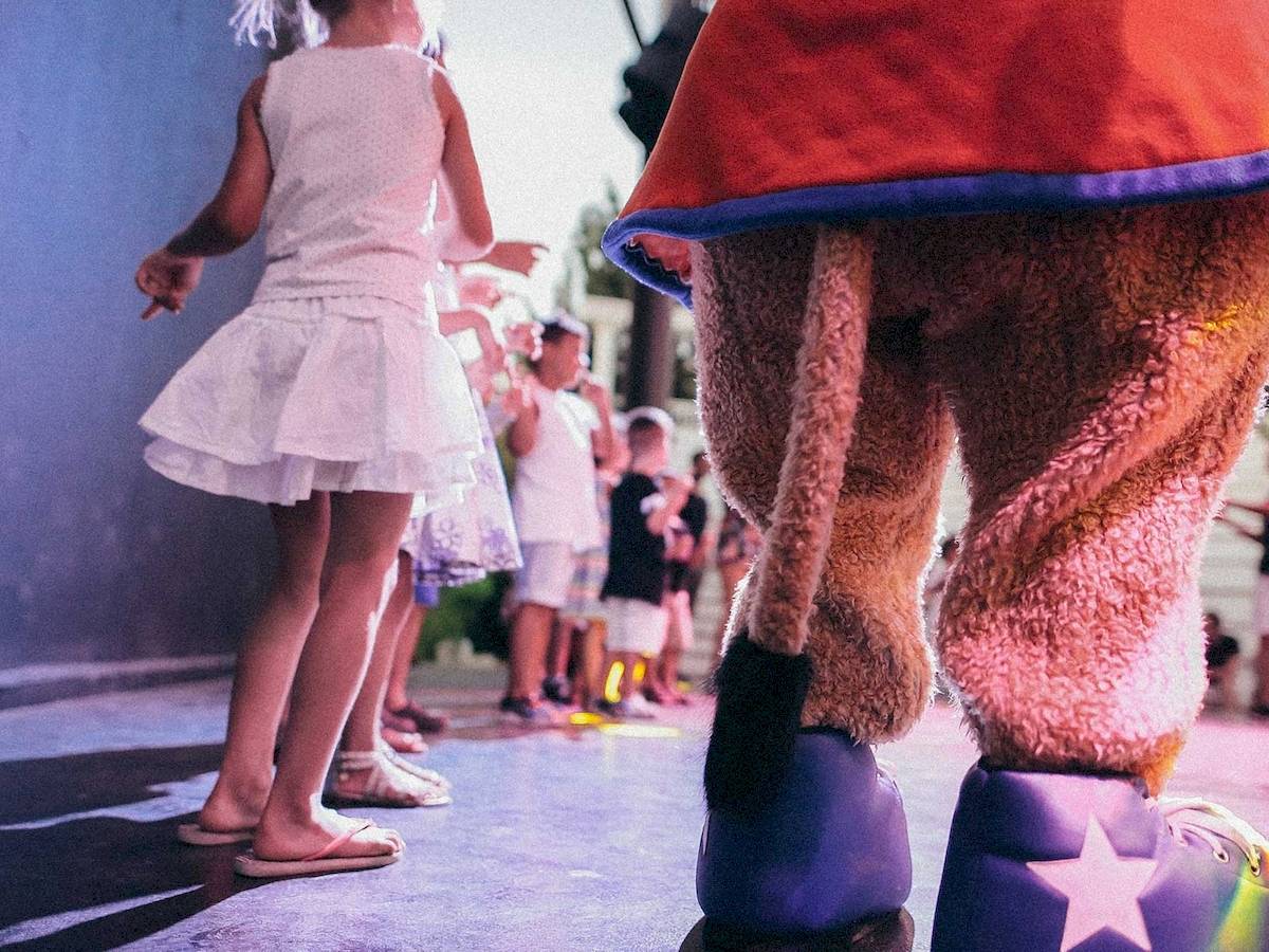 Kinder im Club Marvy tanzen mit einem Charakter in großen Schuhen.