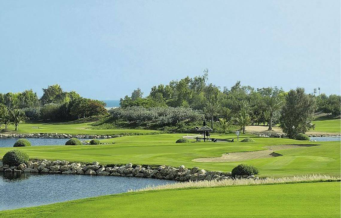 Golfplatz im JA Beach Hotel mit Wasserhindernissen und Bäumen.