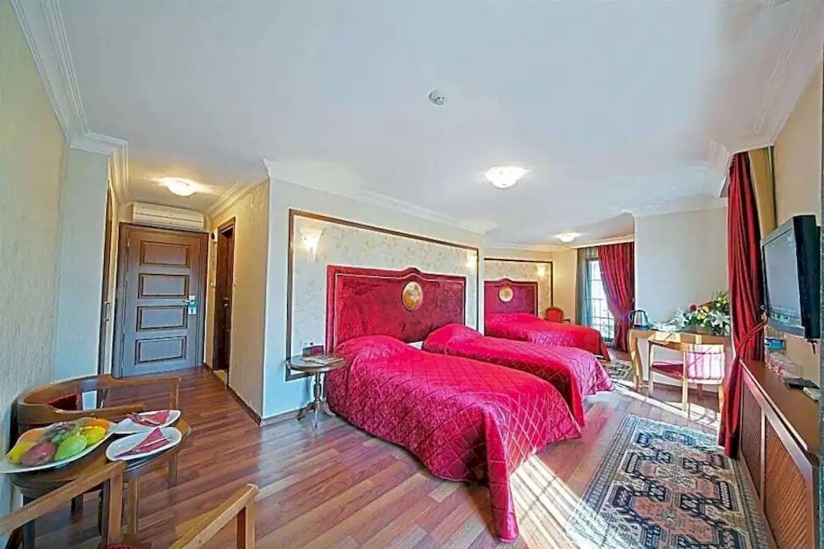 Zwei rote Betten in einem luxuriösen Hotelzimmer des Antea Palace Hotel & Spa.