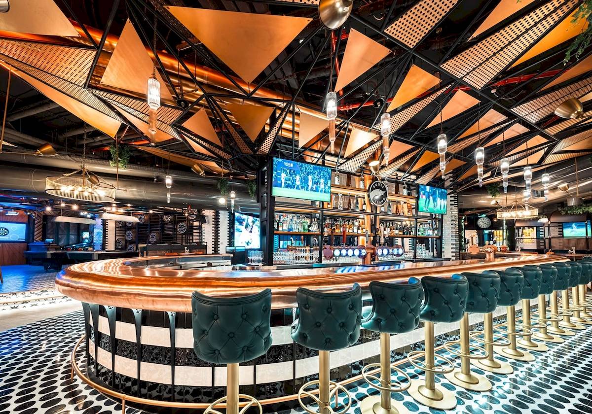 Innenansicht der Bar im FIVE LUXE JBR Hotel mit grünen und goldenen Barhockern und einer Theke.