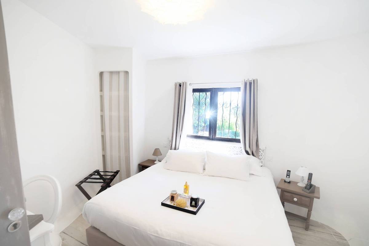 Zimmer im L'Hostellerie du Moulin Hotel mit weißen Wänden, einem großen Bett und einem Nachttisch