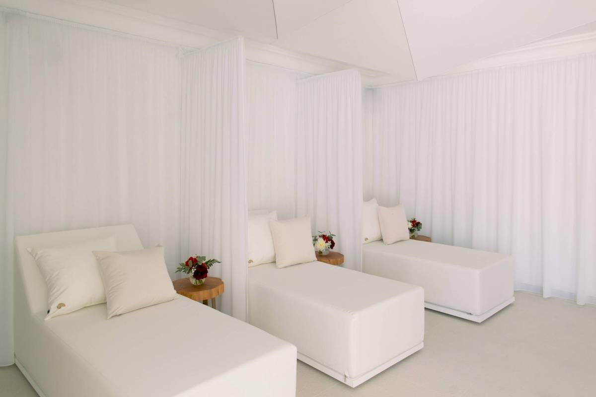 Weißes Hotelzimmer von L'Hostellerie du Moulin mit drei weißen Betten und weißen Vorhängen.